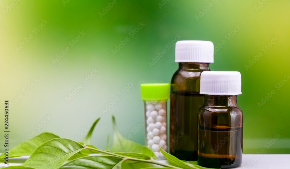 Homeopathy concept – Three bottles of homeopathy substance on green leaf with mix yellow green background Homeopathy concept – Three bottles of homeopathy substance on green leaf with mix yellow green background