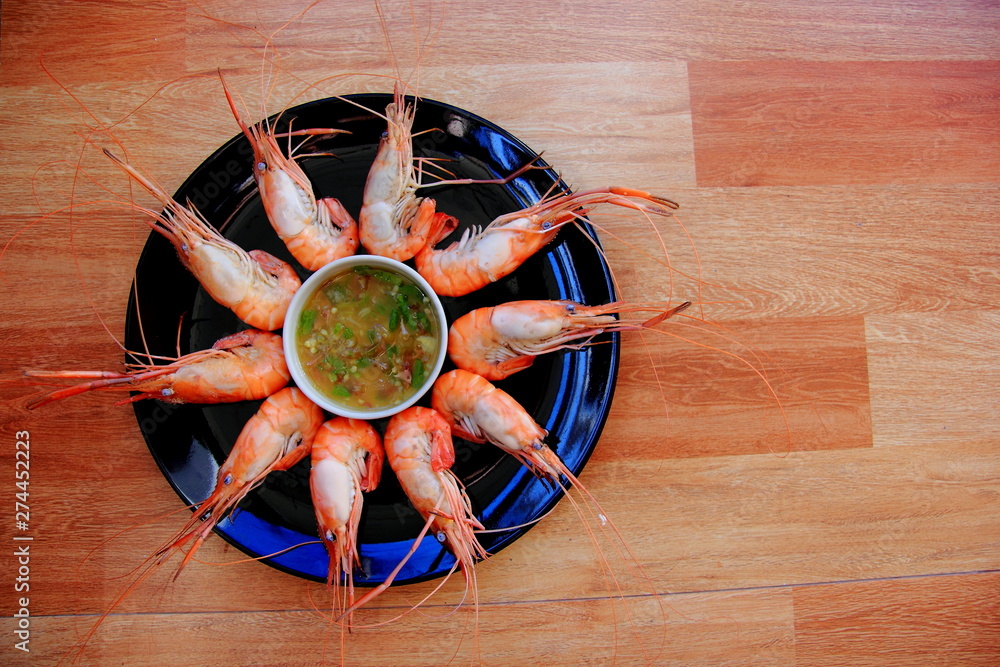 Shrimp is cooked in a black dish, placed on a brown wood floor.