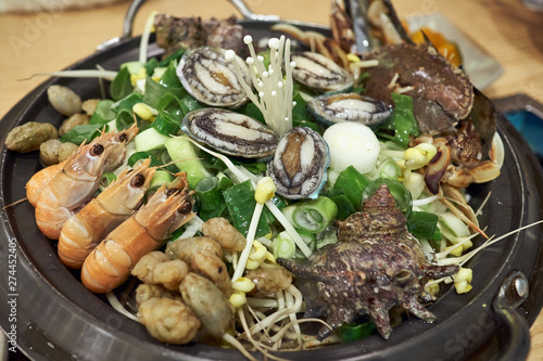 A hot Korean seafood stew with various ingredients including shrimps, avalons, trumpet shells, warty sea squirts, and vegetables.