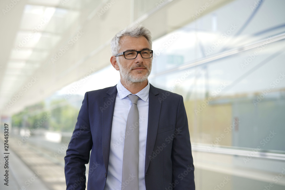 Executive businessman standing outside contemporary office building Executive businessman standing outside contemporary office building