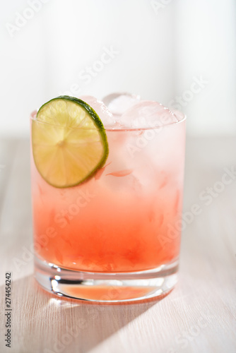 Paloma cocktail served in a tumbler glass. White wooden background, high resolution