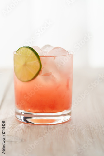 Paloma cocktail served in a tumbler glass. White wooden background, high resolution