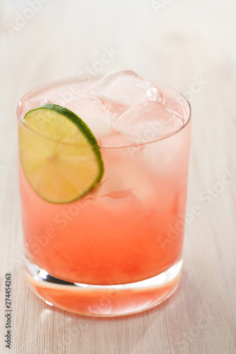 Paloma cocktail served in a tumbler glass. White wooden background, high resolution