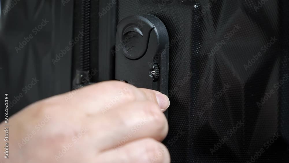Woman enters the code to open suitcase combination lock on the suitcase and presses the button