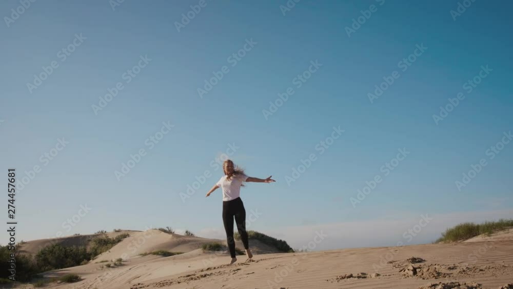 Young beautiful blonde woman spinning around in dance on morning sand hills. Сoncept of happiness and success Young beautiful blonde woman spinning around in dance on morning sand hills. Сoncept of happiness and success