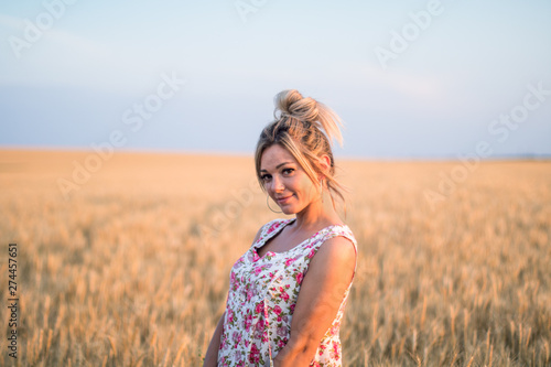 young seductive rural blond hair woman in dress on the yellow wheat field on the sunset