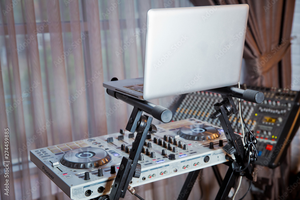 Headphones in foreground and DJ hands in motion . Dj mixes the track in the nightclub at party .