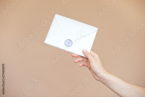 Close-up photo of female hands with wax seal with invitation envelope, gift certificate, postcard, wedding invitation card