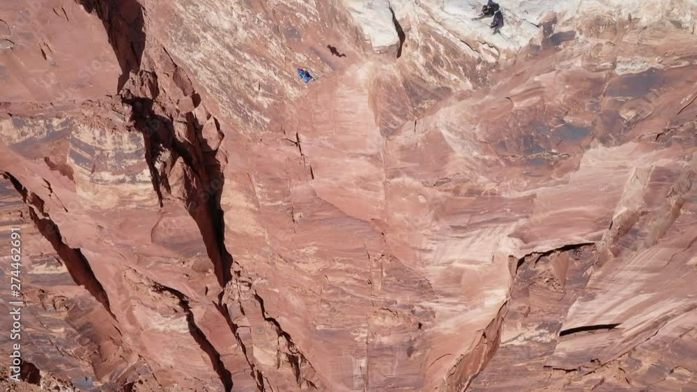 Birds eye view aerial of base jumper running off of cliff in Moab Utah extreme sports Birds eye view aerial of base jumper running off of cliff in Moab Utah extreme sports