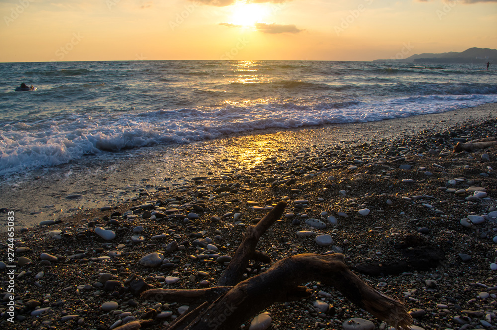 Fototapeta premium Amazing sea sunset on the pebble beach, the sun, waves, clouds