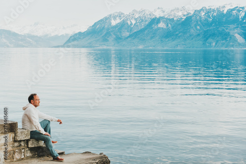 Portrait of handsome man admiring beautiful lake with mountains, wearing white sweatshirt