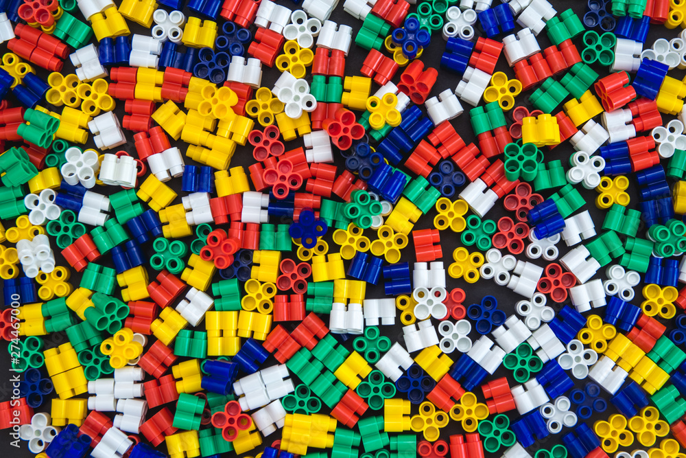 Multicolored plastic building blocks of the designer. Background of plastic colored details building blocks. Parts of bright small spare parts for toys. Top view. Multicolored plastic building blocks of the designer. Background of plastic colored details building blocks. Parts of bright small spare parts for toys. Top view.