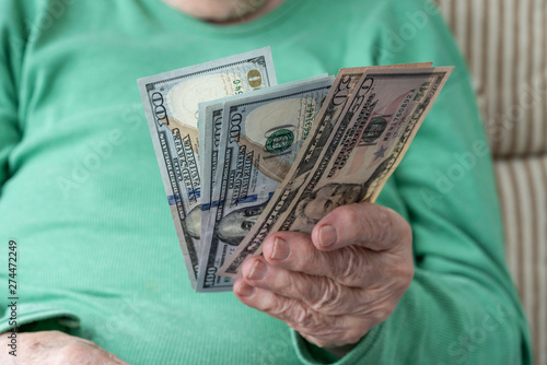 hand of a senior woman holding American Dollars