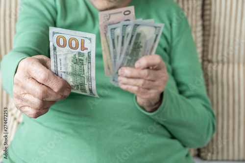 wrinkled hand of a senior woman holding American Dollars