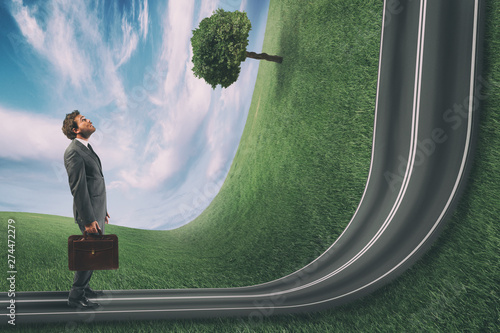 Businessman observes the road uphill in front of him. Achievement business goal and difficult career concept