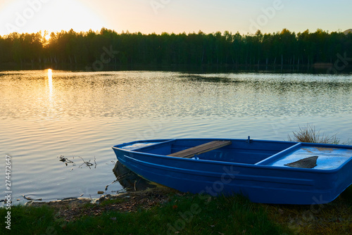 fishing boat in a calm lake water/old fishing boat/ wooden fishing boat in a still lake water 