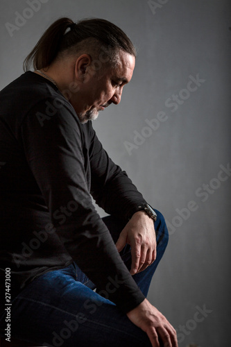 Sad middle-aged man with long hair. Low key. Vertical. © Анна Демидова