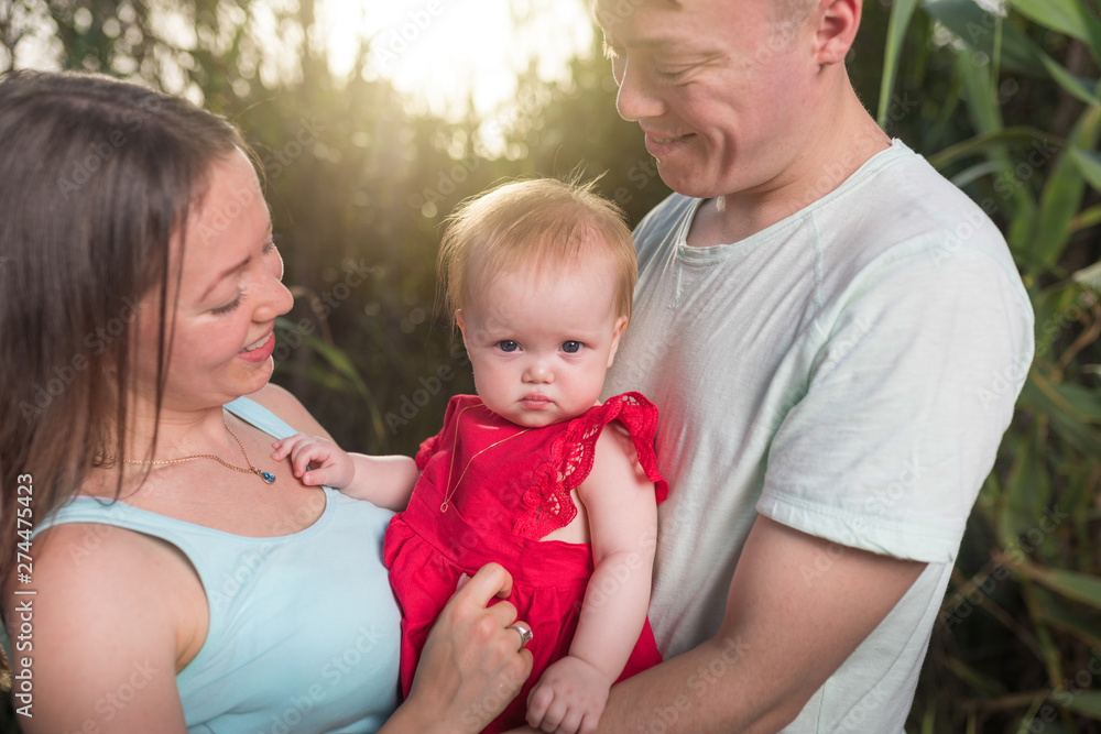 Happy family outdoor. Parents hold child on hands and rejoice. They are happy together Happy family outdoor. Parents hold child on hands and rejoice. They are happy together
