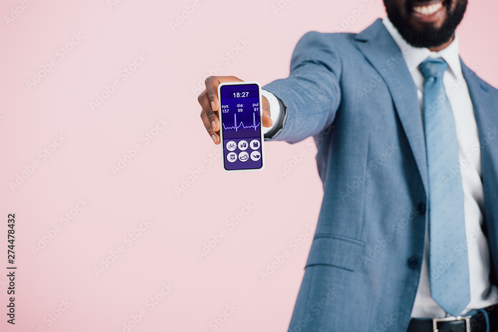 cropped view of african american businessman in suit showing smartphone with health app, isolated on pink cropped view of african american businessman in suit showing smartphone with health app, isolated on pink