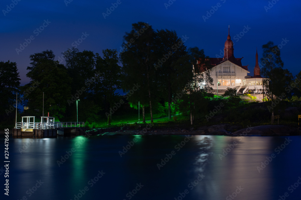 A beautiful old illuminated wooden building on an island during night time.