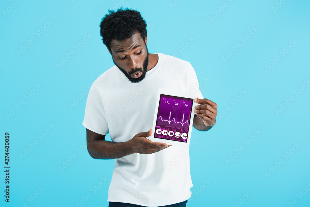 shocked african american man showing digital tablet with health app, isolated on blue shocked african american man showing digital tablet with health app, isolated on blue