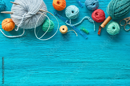 Various wool yarn, knitting needles and stuffed heart on mint textured background