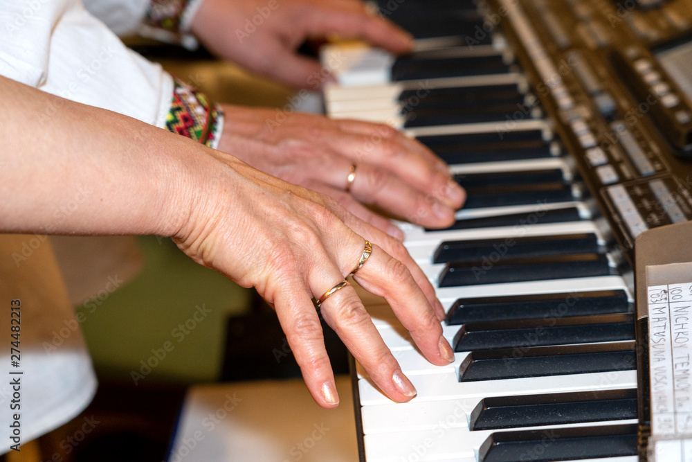 Fototapeta premium Close up of musician hands classic piano playing. Musician hands. Scene of pianist hands. Male musician playing midi keyboard synthesizer in recording studio. Pianist's hands playing the melody .