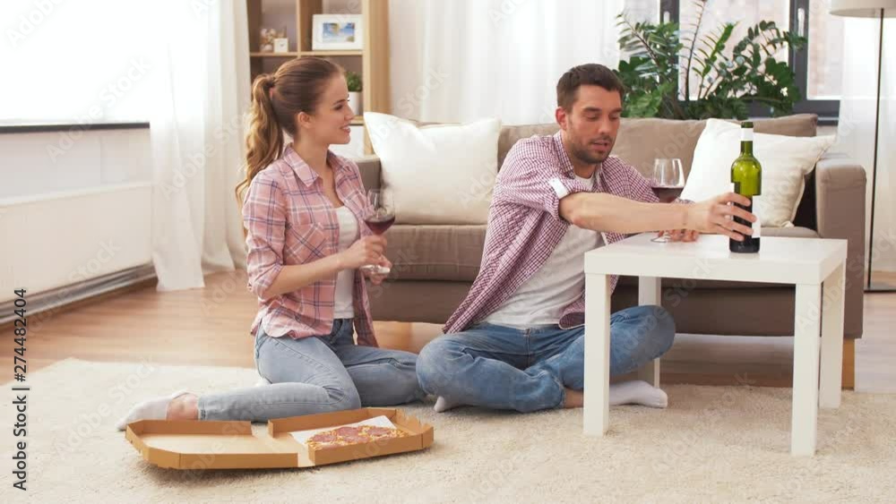 leisure, people and valentines day concept - happy couple with takeaway pizza drinking wine at home leisure, people and valentines day concept - happy couple with takeaway pizza drinking wine at home