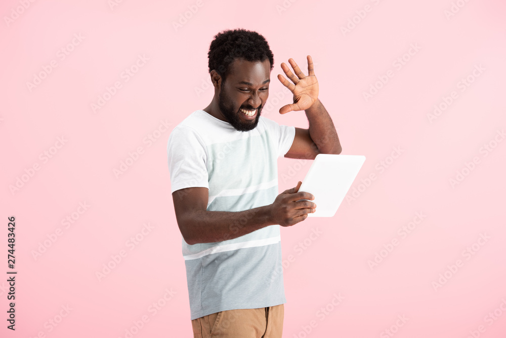 happy african american man gesturing and having video chat on digital tablet isolated on pink