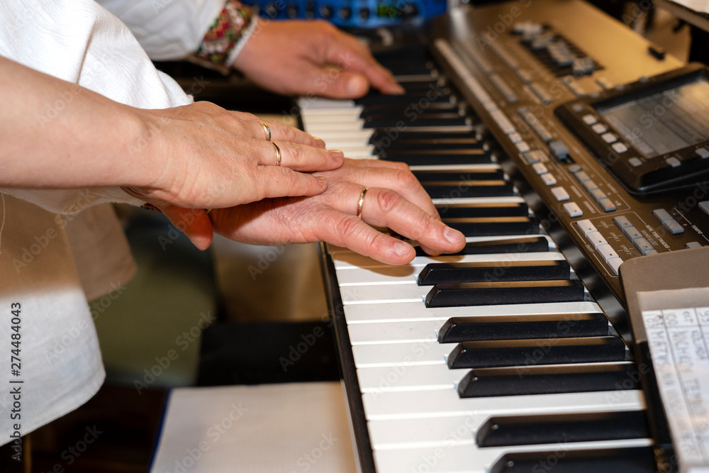 Fototapeta premium Close up of musician hands classic piano playing. Musician hands. Scene of pianist hands. Male musician playing midi keyboard synthesizer in recording studio. Pianist's hands playing the melody .
