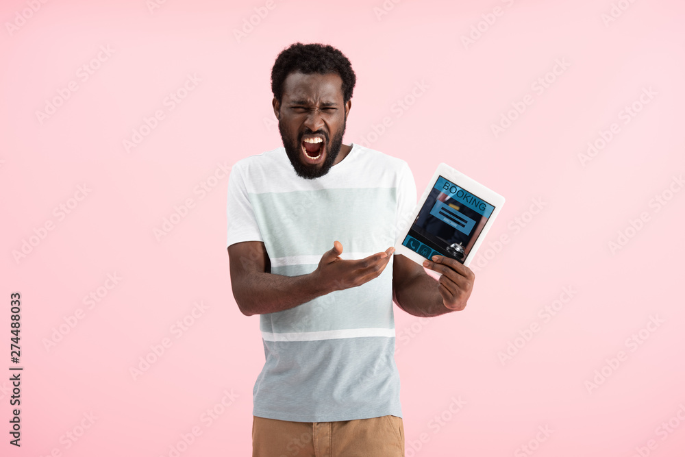 emotional african american man screaming and showing digital tablet with booking app, isolated on pink emotional african american man screaming and showing digital tablet with booking app, isolated on pink