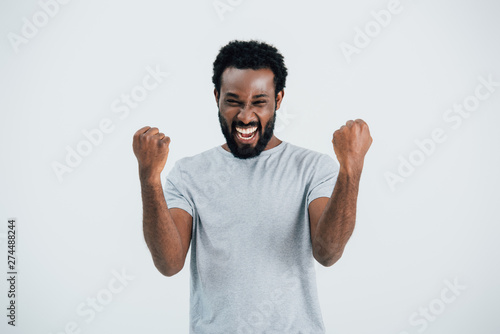 excited african american man in grey t-shirt posing isolated on grey