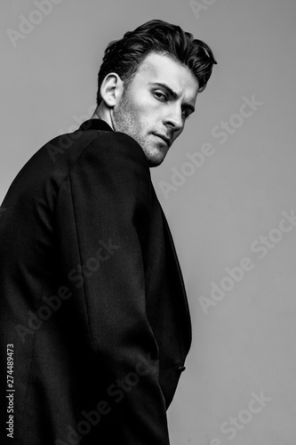 Portrait of young and handsome model with a strong look in a classic black style clothing. Studio shot. Copy space.