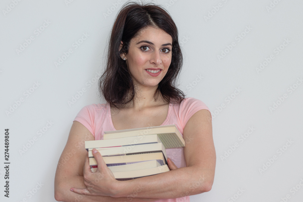 young brunette caucasian girl wearing a plain pink t-shirt carrying some books and smiling, white background. young brunette caucasian girl wearing a plain pink t-shirt carrying some books and smiling, white background.