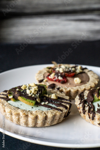 Raw vegan tartlets on the white plate. Healthy desserts  close up