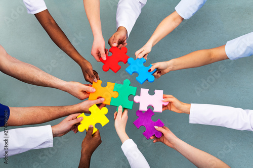 High Angle View Of Medical Team Solving Jigsaw Puzzle photo