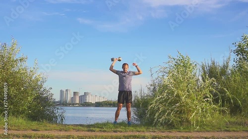 A young man with a cup in his hands rejoices in sports victory on background of the evening Minsk. Concept as victory, success and champion in sport. Slow motion. European Olympic Games in Minsk 2019.