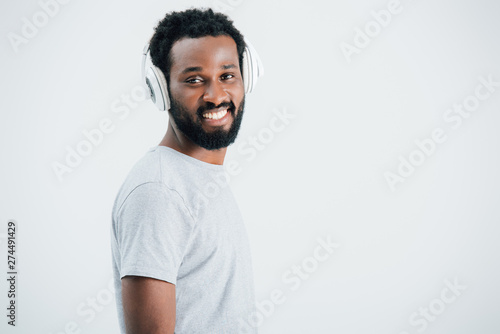 smiling african american man listening music with headphones, isolated on grey © LIGHTFIELD STUDIOS