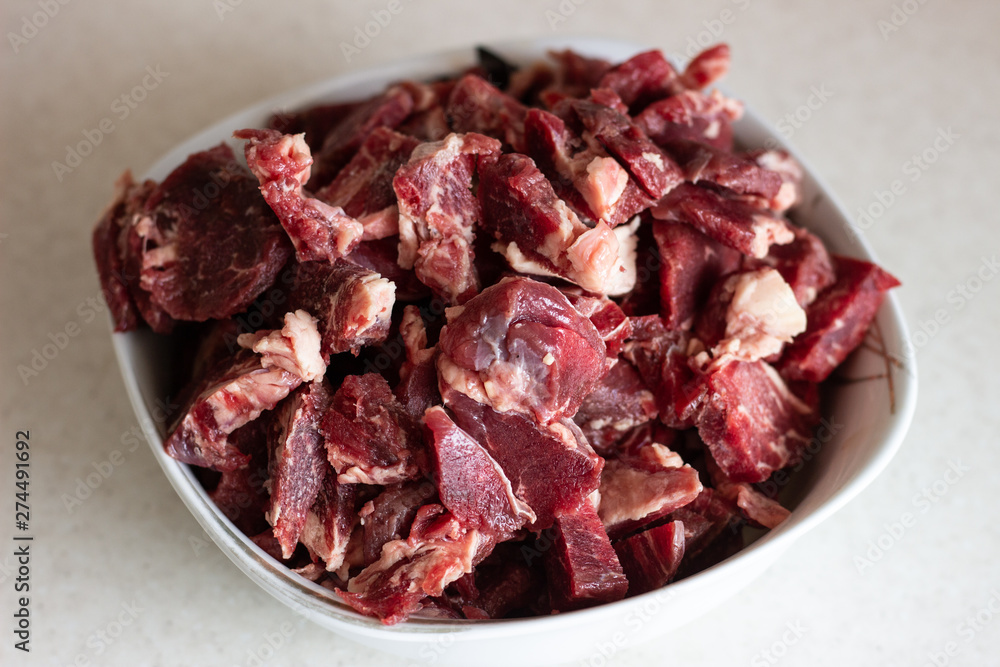 Raw meat in a plate on a white surface. Raw meat in a plate. Beef meat on a plate Raw meat in a plate on a white surface. Raw meat in a plate. Beef meat on a plate