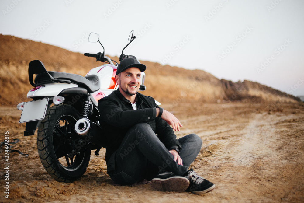 Obraz premium Smiling happy biker in sitting on motorcycle on road