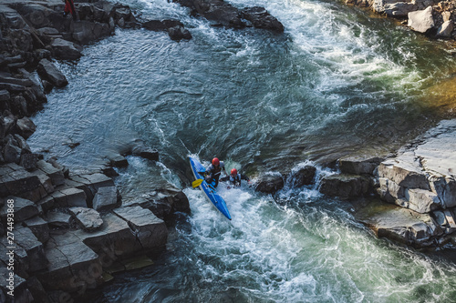 Two man on whitewater catamaran are going through the rapid on the mountain river in early spring