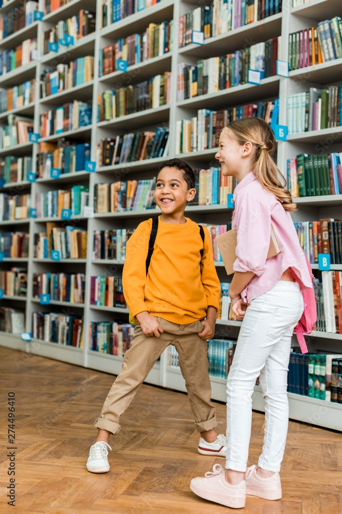 cute multicultural kids standing and smiling in library cute multicultural kids standing and smiling in library