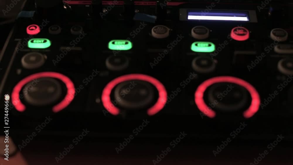 Closeup on a modern electronical musical device for making beats and loop samples with knobs and blinking buttons at the nightclub Closeup on a modern electronical musical device for making beats and loop samples with knobs and blinking buttons at the nightclub