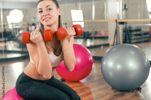 Young sporty woman in gym doing fitness exercices with pink ball