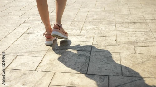 feet close up, pedestrians walk down the street. Girl's legs in pink leather sandals on a white high platform. Summer street fashion concept. Legs and shoes