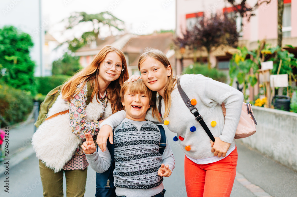 Φωτογραφία Group of 3 funny kids with backpacks, 2 schoolgirls and one preschooler, back to