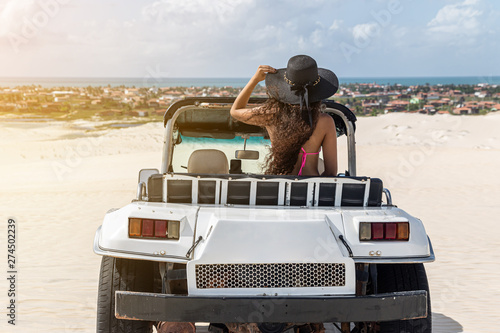 Beautiful happy young woman with buggy ride through the dunes of the coast of Brazil. photo