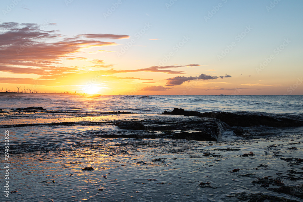 Scenic sunset over the sea. The sun sets on the water. Clouded sky is painted with bright colors. Sunset beach in a summer evening. Brazil. Scenic sunset over the sea. The sun sets on the water. Clouded sky is painted with bright colors. Sunset beach in a summer evening. Brazil.