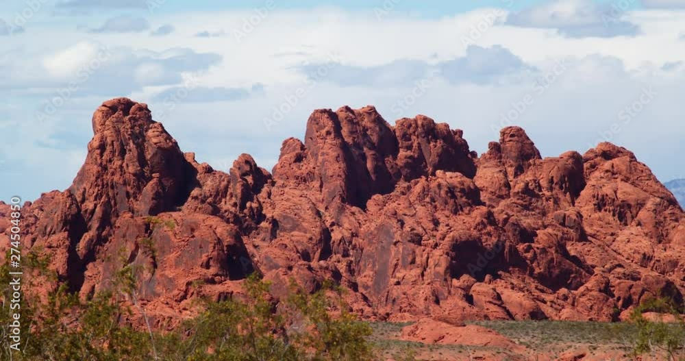 Jagged red rock hill in distance, telephoto