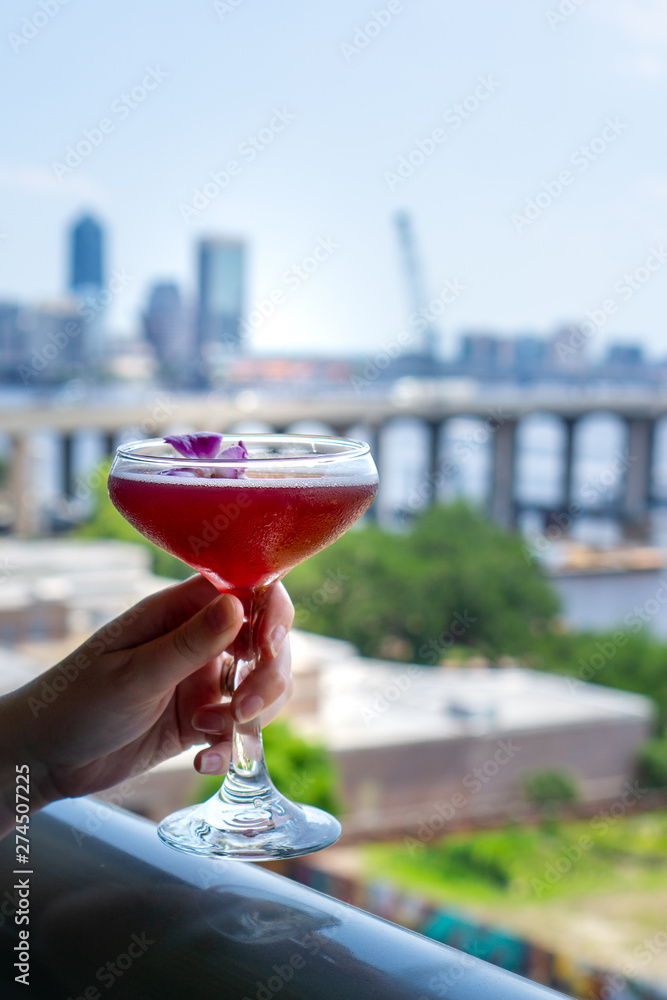 Woman holding cocktail overlooking cityscape Woman holding cocktail overlooking cityscape